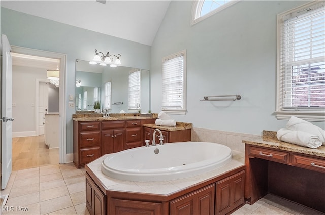 bathroom with tile patterned flooring, vanity, lofted ceiling, and a bath