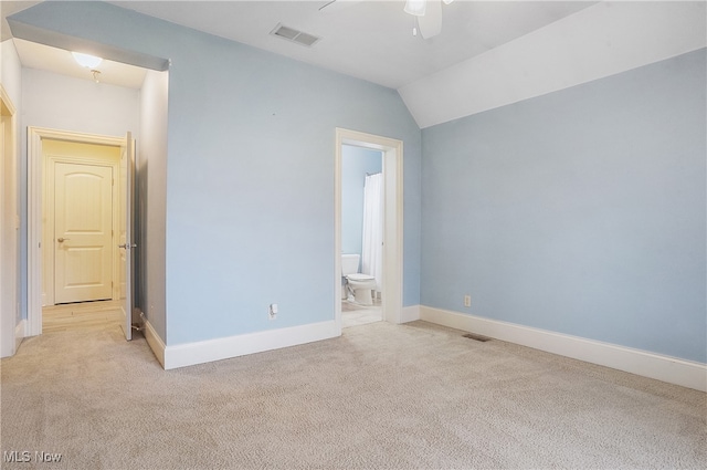 unfurnished bedroom featuring vaulted ceiling, light carpet, connected bathroom, and ceiling fan