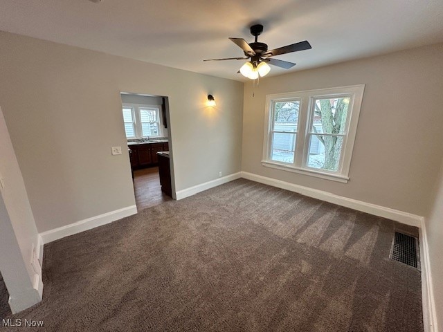 carpeted empty room with a wealth of natural light and ceiling fan