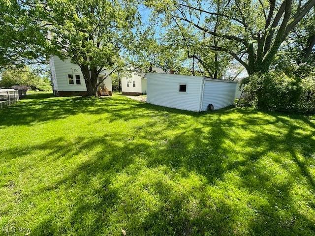 view of green lawn featuring an outbuilding
