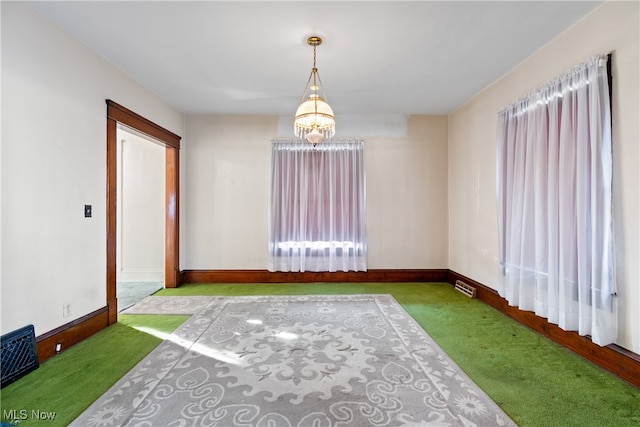 carpeted empty room featuring a notable chandelier