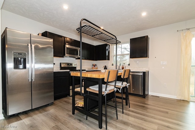 kitchen with appliances with stainless steel finishes, a textured ceiling, and light hardwood / wood-style floors