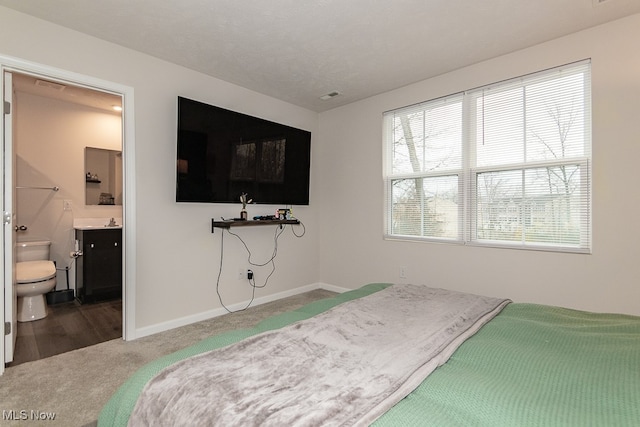 carpeted bedroom with connected bathroom and a textured ceiling