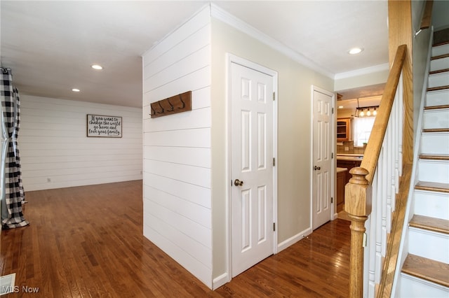 corridor with wood walls, ornamental molding, and dark wood-type flooring