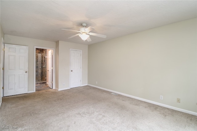 unfurnished bedroom with carpet flooring, a textured ceiling, ceiling fan, connected bathroom, and a closet