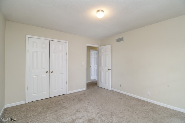 unfurnished bedroom with light carpet and a closet