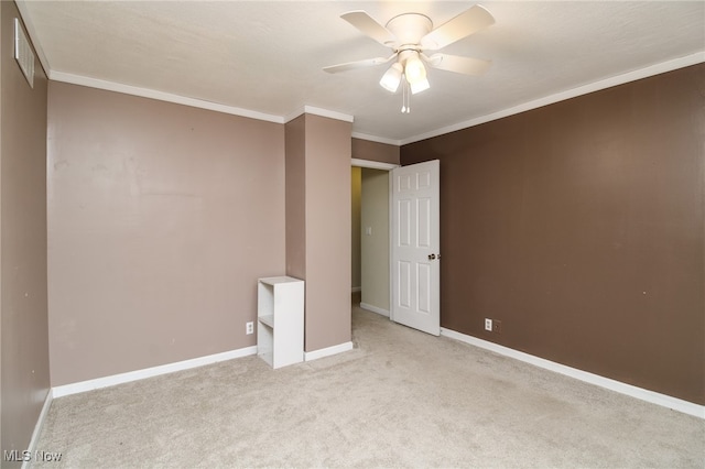 carpeted spare room with ceiling fan and crown molding