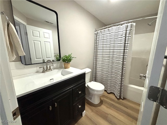 full bathroom featuring hardwood / wood-style floors, vanity, shower / tub combo with curtain, and toilet