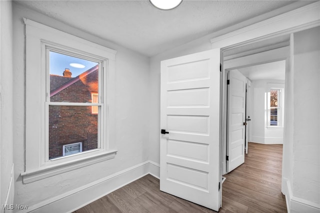 corridor with hardwood / wood-style floors, a textured ceiling, and vaulted ceiling