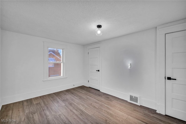 empty room featuring wood-type flooring and a textured ceiling