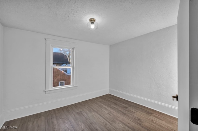 spare room featuring wood-type flooring and a textured ceiling