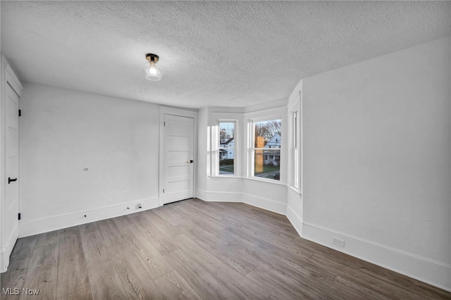 empty room featuring wood-type flooring and a textured ceiling