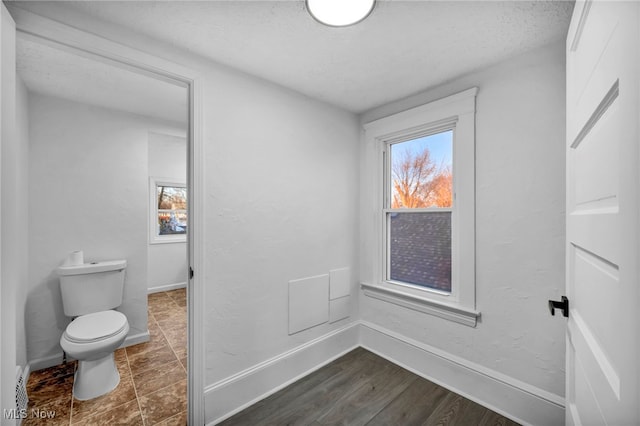 bathroom with toilet, wood-type flooring, and a textured ceiling