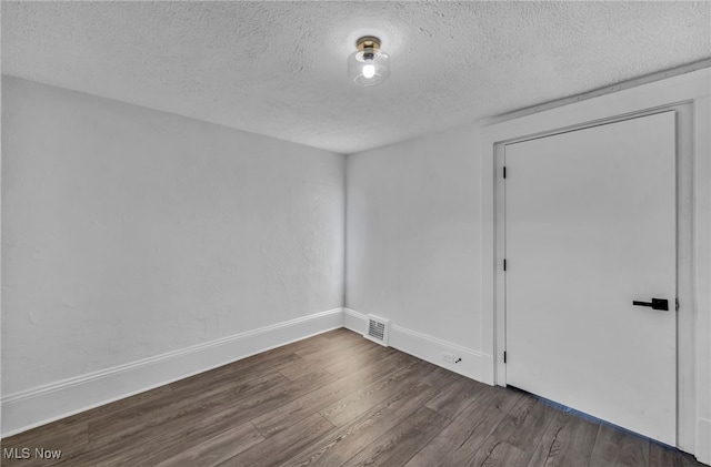 empty room with dark wood-type flooring and a textured ceiling