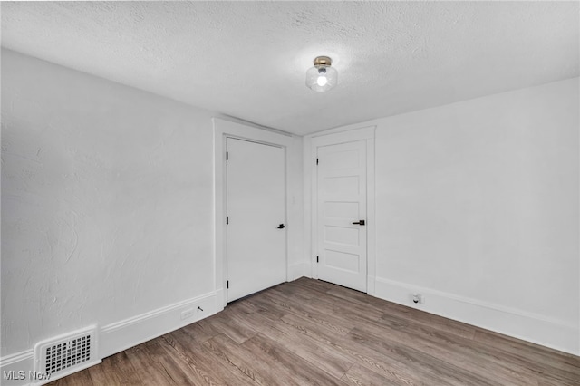 spare room featuring a textured ceiling and hardwood / wood-style flooring