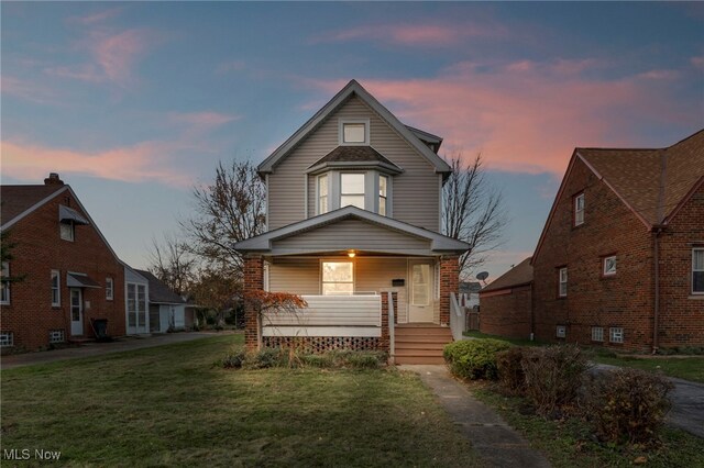 view of front of house with covered porch and a yard