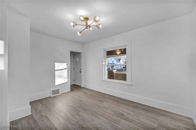 empty room featuring light hardwood / wood-style flooring and a notable chandelier