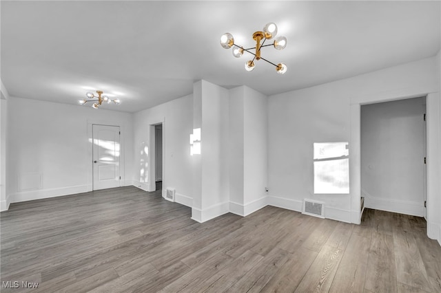 unfurnished living room featuring a notable chandelier, plenty of natural light, and wood-type flooring