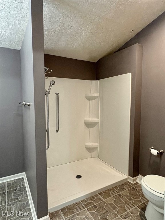 bathroom with a shower, a textured ceiling, and toilet