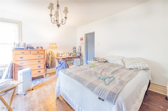 bedroom featuring radiator heating unit, dark hardwood / wood-style floors, and a notable chandelier