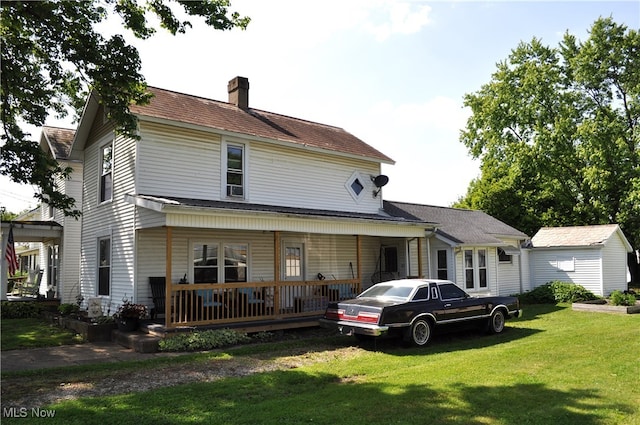 rear view of property featuring a yard and covered porch