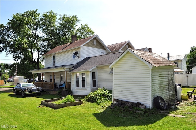 rear view of house featuring covered porch and a yard