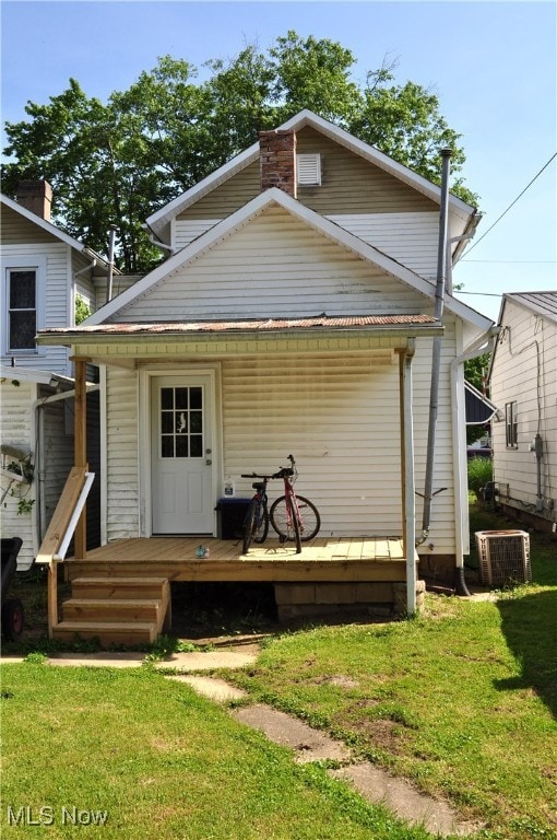 rear view of house with central air condition unit and a lawn