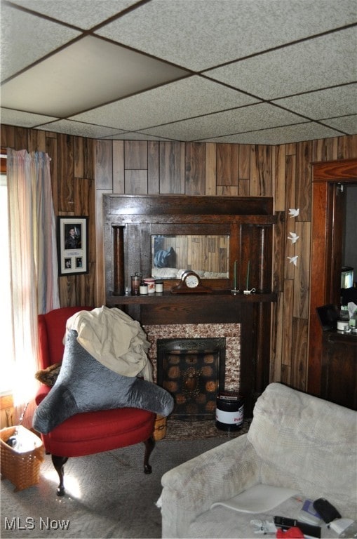 sitting room featuring a fireplace, a paneled ceiling, and wood walls