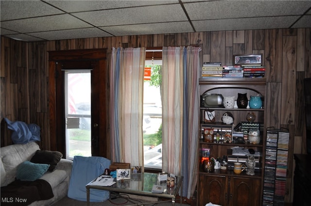 interior space featuring a paneled ceiling, plenty of natural light, and wooden walls