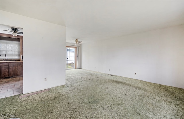 unfurnished room featuring carpet, ceiling fan, and sink