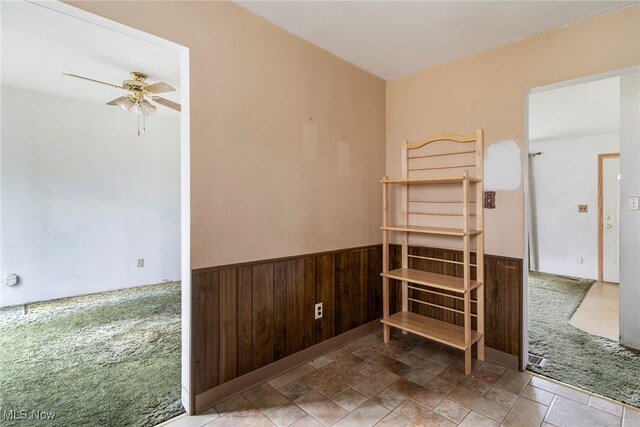 bedroom featuring carpet flooring, ceiling fan, and wood walls