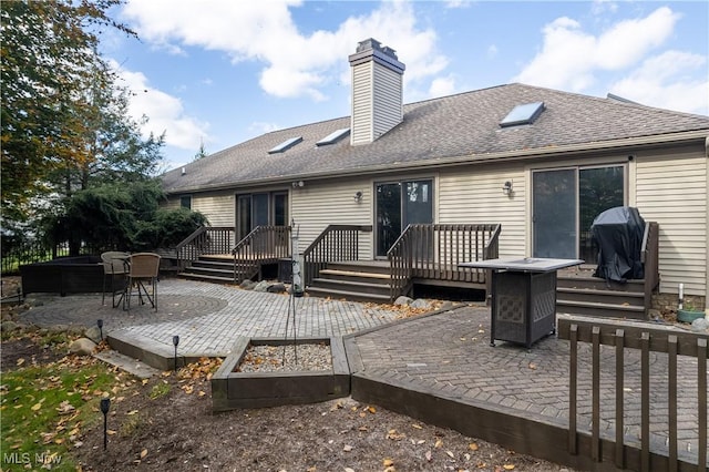 rear view of house with a patio area, a wooden deck, and an outdoor fire pit