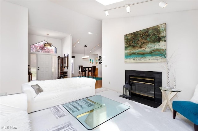 carpeted living room with rail lighting and vaulted ceiling