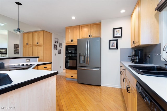 kitchen with pendant lighting, black appliances, sink, light brown cabinetry, and light hardwood / wood-style floors