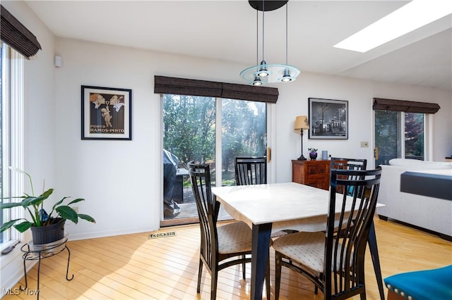 dining space featuring light hardwood / wood-style flooring and a skylight