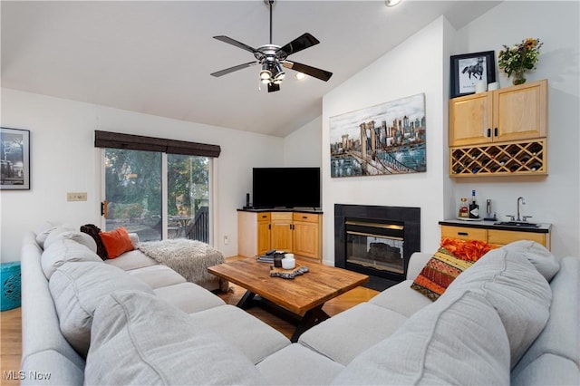 living room with indoor wet bar, ceiling fan, vaulted ceiling, and hardwood / wood-style flooring