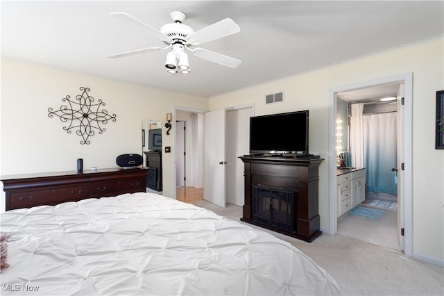 carpeted bedroom featuring ensuite bath and ceiling fan