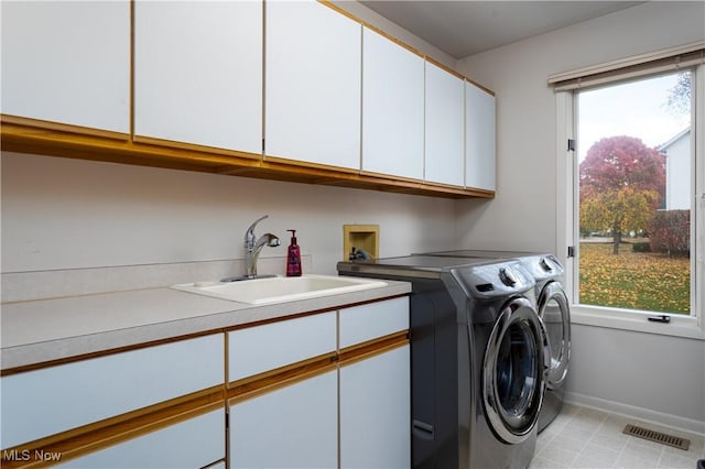 washroom with cabinets, independent washer and dryer, a wealth of natural light, and sink