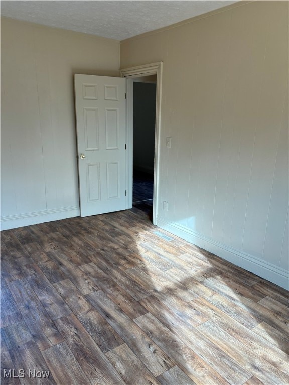 empty room with a textured ceiling and dark hardwood / wood-style floors