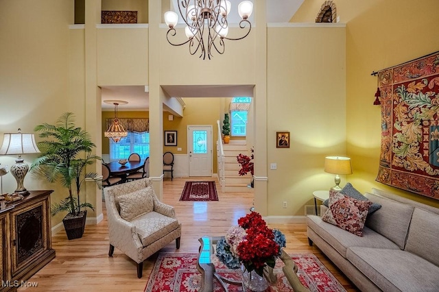 living room with light wood finished floors, baseboards, a high ceiling, and a chandelier