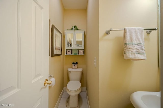 half bathroom with baseboards, toilet, and tile patterned floors