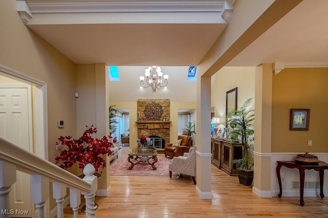 interior space with a chandelier, a stone fireplace, visible vents, baseboards, and light wood-style floors