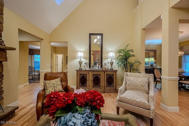 living area featuring high vaulted ceiling, baseboards, and wood finished floors