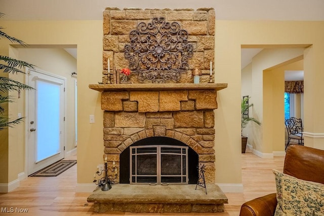 interior details with a stone fireplace, baseboards, and wood finished floors