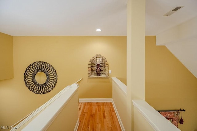 corridor with light wood-style flooring, recessed lighting, visible vents, an upstairs landing, and baseboards