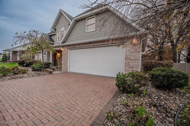 view of front of property featuring a garage, decorative driveway, and brick siding