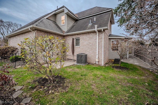 rear view of house featuring brick siding, a yard, a patio, central air condition unit, and fence