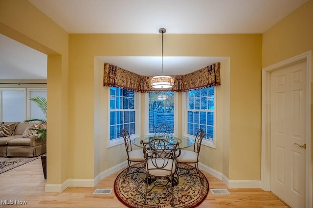 dining space featuring visible vents, light wood-style flooring, and baseboards