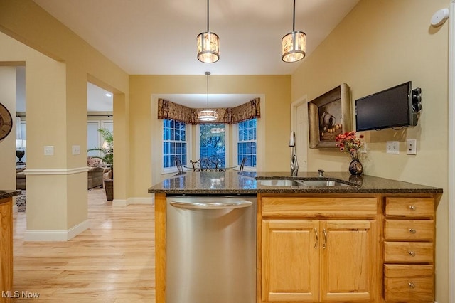 kitchen featuring decorative light fixtures, light wood-style flooring, stainless steel dishwasher, a sink, and dark stone counters