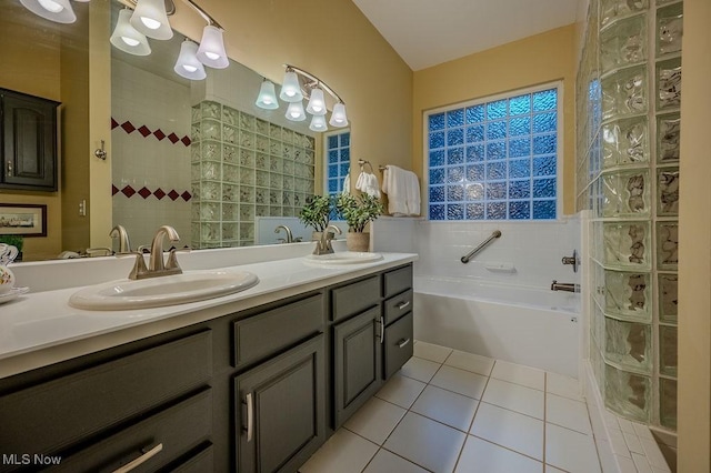 full bath featuring double vanity, a garden tub, a sink, and tile patterned floors